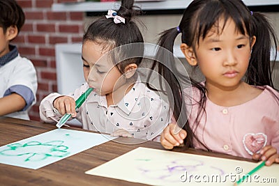 group of Cute little girl and boy student blowing color pen painting together with nursery teacher in classroom school . Happy Stock Photo