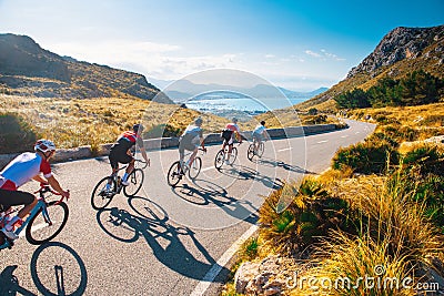 Group of cyclist ride together on road bicycles in beautiful nature. Sunset light, sea in background Editorial Stock Photo