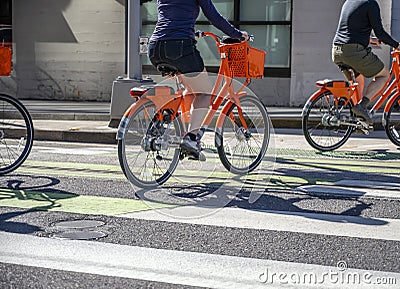 Group of cyclists on rented public bikes cross the road at crossroads Stock Photo