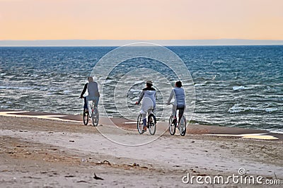 Group of cyclists riding bicycles along the seaside in the evening. Editorial Stock Photo