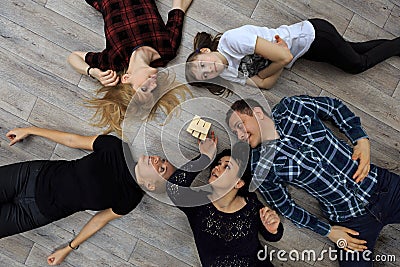 Group of different friends, adults and child, play bricks game on floor Stock Photo