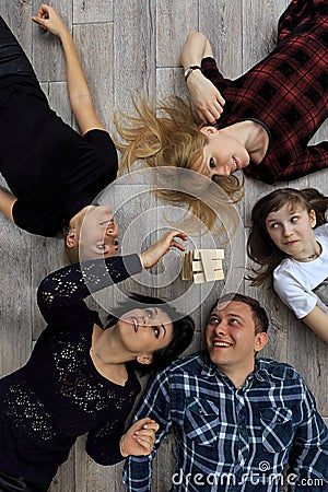 Group of different friends, adults and child, play bricks game on floor Stock Photo