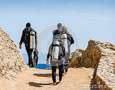 Group of divers with equipment for diving go to the sea against the blue sky and clouds in Egypt Dahab South Sinai Editorial Stock Photo