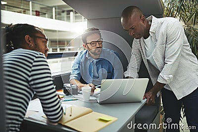 Designers working on a laptop in an office meeting pod Stock Photo