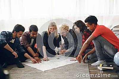 Group of diverse friends looking at map in the bright room Stock Photo