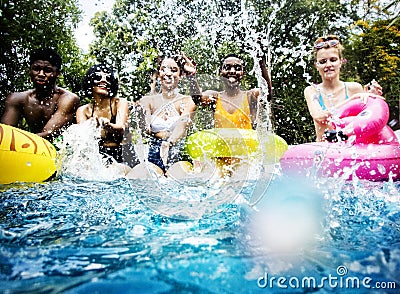 Group of diverse friends splashing water at the swimming pool Stock Photo