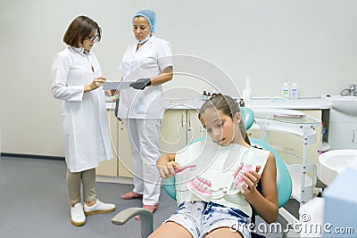 Group of doctors looking at x-ray. Dental office, child patient in armchair. Healthcare, medical and dentistry concept Stock Photo