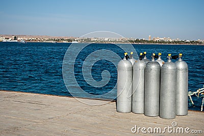 Group eight cylinders with air. eight aluminum cylinders on sea dock. Blue ocean and white steel cylinders Stock Photo