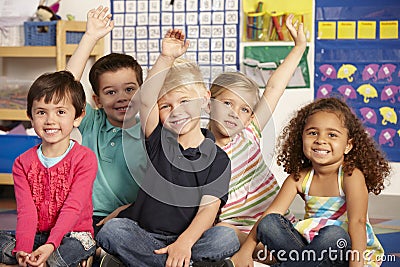 Group Of Elementary Age Schoolchildren Answering Question In Class Stock Photo