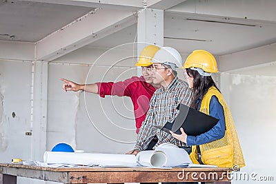 Group of engineer checking the blueprint on the table and talking about construction project with commitment to success at Stock Photo