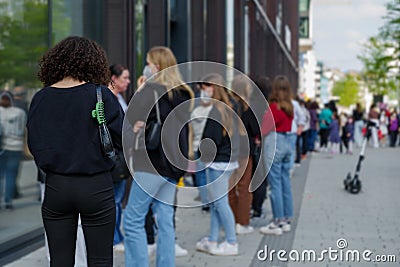 Group of European women with protective face mask queue and wait for shopping on sidewalk outside store during lockdown. Editorial Stock Photo