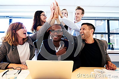 Group of executives high fiving over colleague's head Stock Photo