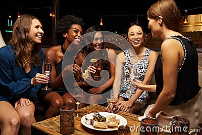 Group Of Female Friends Enjoying Night Out At Rooftop Bar Stock Photo