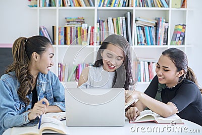Group of female students using a laptop in library Stock Photo