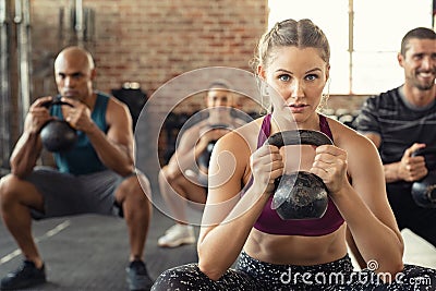 Fitness woman squatting with kettle bell Stock Photo