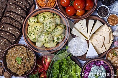 Group food on table: boiled young potatoes, beans, braised cabbage, beet salad with cottage cheese, sliced cheeses, tomato, korean Stock Photo