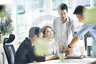 Group of four asian teammates working together discussing business in office Stock Photo