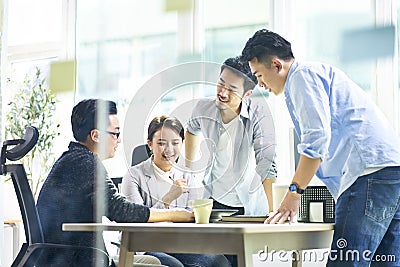 Group of four asian teammates working together discussing business in office Stock Photo