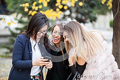 Group of four girl friends looking at phone on the selfie they w Stock Photo