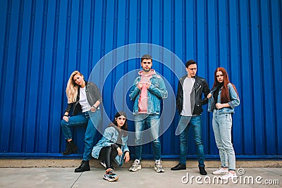 Group of four young diverse friends in jeanse outfit look carefree, young and happy on city`s streets Stock Photo