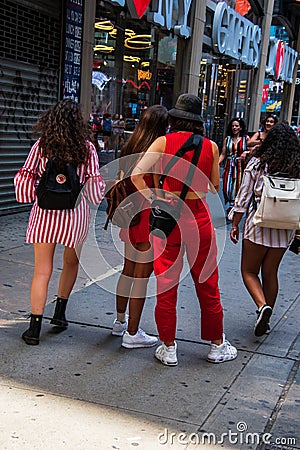 Group of four young girls seen from the back wearing backpacks walking on a Manhattan, New York city sidewalk Editorial Stock Photo