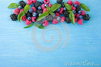 Group of fresh summer berries with basil`s on a blue background. Ripe blueberries, raspberries and blackberries. Stock Photo