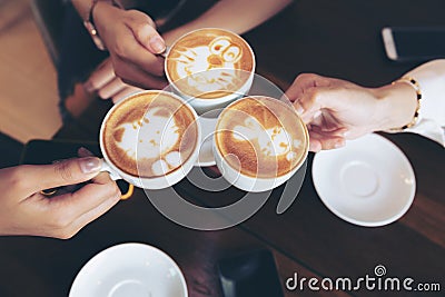 Group of friends cheers with latae cup in cafe bar with phone on table sitting intdoor at cafe - Young girl group having fun Stock Photo