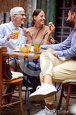 A group of friends of different generations talking while they have a drink in the bar. Leisure, bar, friendship, outdoor Stock Photo