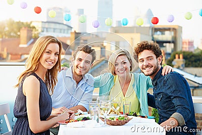 Group Of Friends Eating Meal On Rooftop Terrace Stock Photo