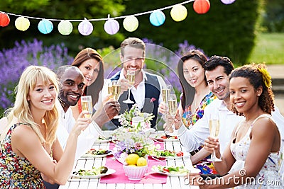 outdoor friends dinner enjoying champagne holding smiling camera glass