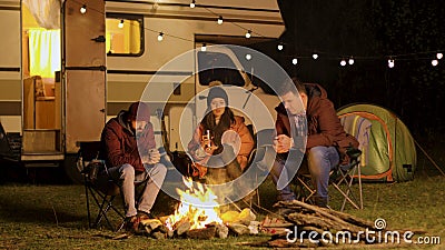 Group of friends gathered around camp fire in a cold night of autumn Stock Photo