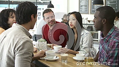 Group Of Friends Meeting In Coffee Shop. Group of friends sitting at table in café chatting.Shot on Sony FS700 in PAL format at a frame rate of 25fps stock video footage Group Of Friends Meeting In Coffee Shop. Group of friends sitting at table in café chatting.Shot on Sony FS700 in PAL format at a frame rate of 25fps stock video footage