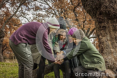 Group of friends sit on a trunk of a tree doing a pile of hands. Stock Photo