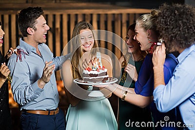 Group of friends surprising a woman with birthday cake Stock Photo