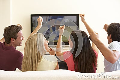 Group Of Friends Watching Widescreen TV At Home Stock Photo