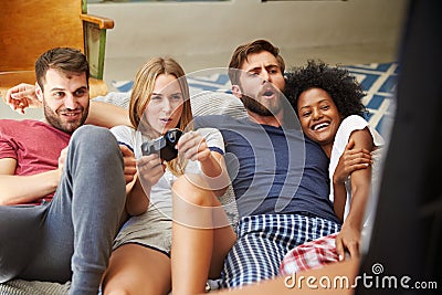 Group Of Friends Wearing Pajamas Playing Video Game Together Stock Photo