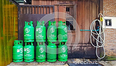 Group of green gas tank with wooden background putting near water pipeline and entrance toile or washroom. Editorial Stock Photo