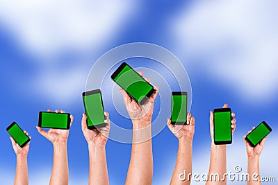 group of hands Raising up Smart phones against green background - Hands holding phones Stock Photo