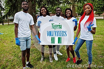 Group of happy african volunteers hold blank with Nigeria flag in park. Africa countries volunteering, charity, people and ecology Stock Photo