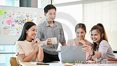A group of happy Asian tech developers is in the meeting, brainstorming on a new UI and UX project Stock Photo