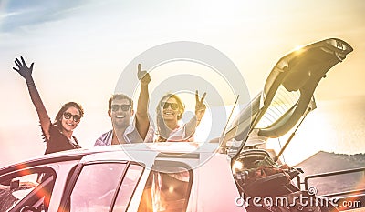 Group of happy best friends cheering on car road trip at sunset Stock Photo