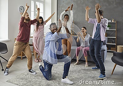 Group of happy friends applauding a funny black man while dancing at a party at home Stock Photo