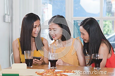 Group of happy friends eating dinner together and girl taking photo of food on the table Stock Photo