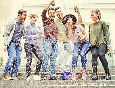 Group of happy friends having a street party drinking beers while confetti are falling down Stock Photo