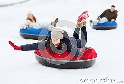 Group of happy friends sliding down on snow tubes Stock Photo