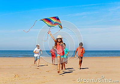 Group of happy kids run with kite on the beach Stock Photo