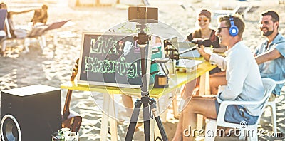 Group of happy people making a video feed online at beach party - Speaker and friends starting live social streaming - New media Stock Photo