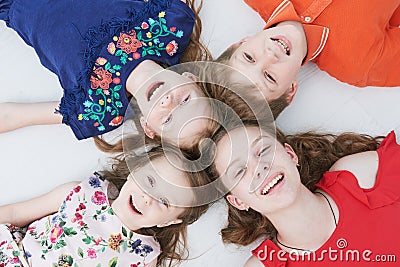 Group of smiling four kids laying on floor. Upper view Stock Photo