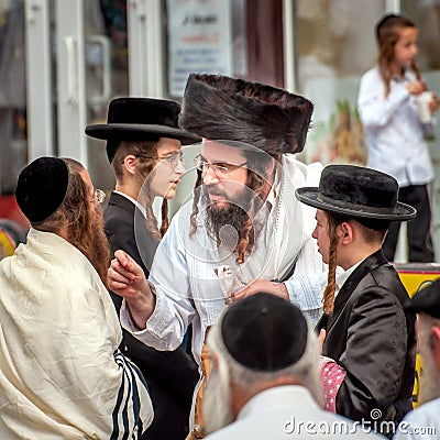 A group of Hasidim pilgrims in traditional clothing emotionally talk. Rosh hashanah holiday, Jewish New Year. Editorial Stock Photo