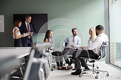 Group Having Discussion At Graduate Recruitment Assessment Day Whilst Being Observed By Recruitment Team Stock Photo